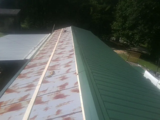 Old rusted panels beside newly installed green metal roofing — Wind Damage Roof Repair by Roofing Brothers in West Chesterfield