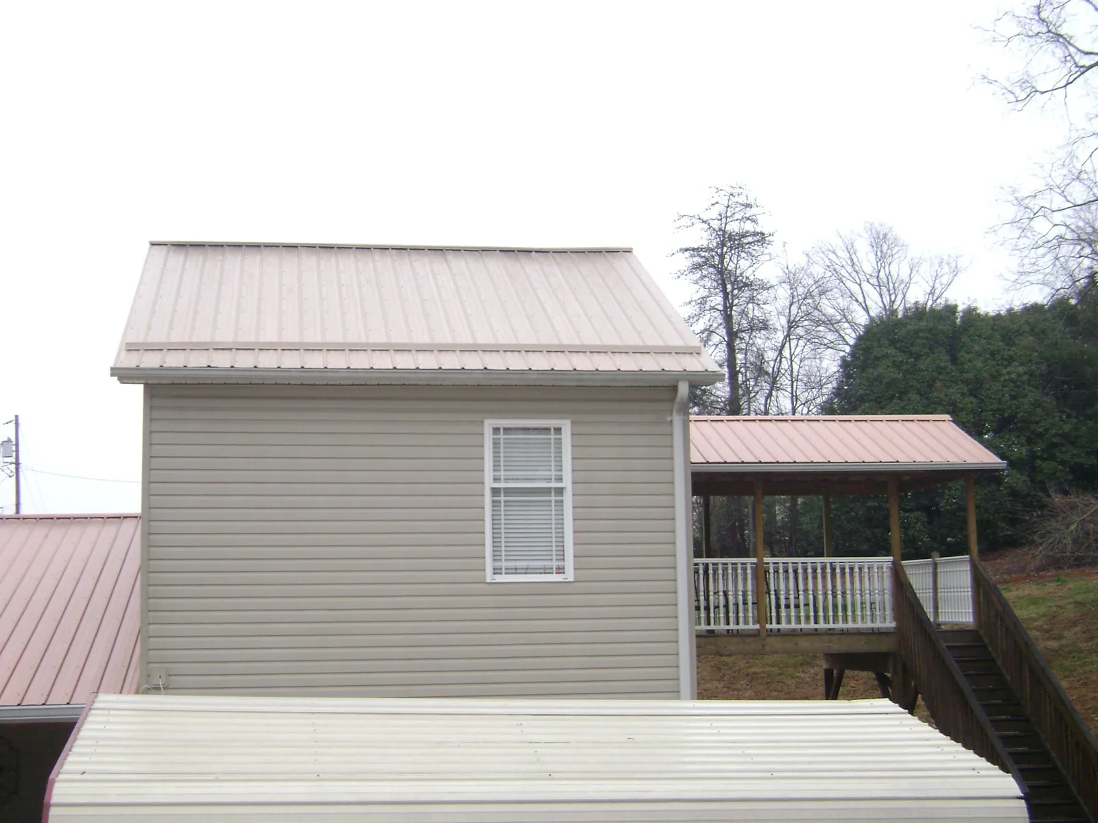 Tan metal roofs on a two story addition and attached porch, from a Roof Replacement job in West Chesterfield